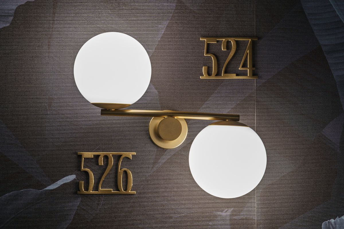 Segnaletica suite in ottone su parete in marmo.