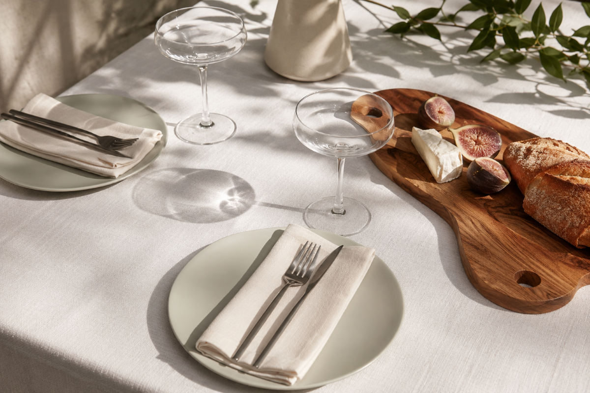 Elegant mise en place with a linen tablecloth, natural light and refined tableware.