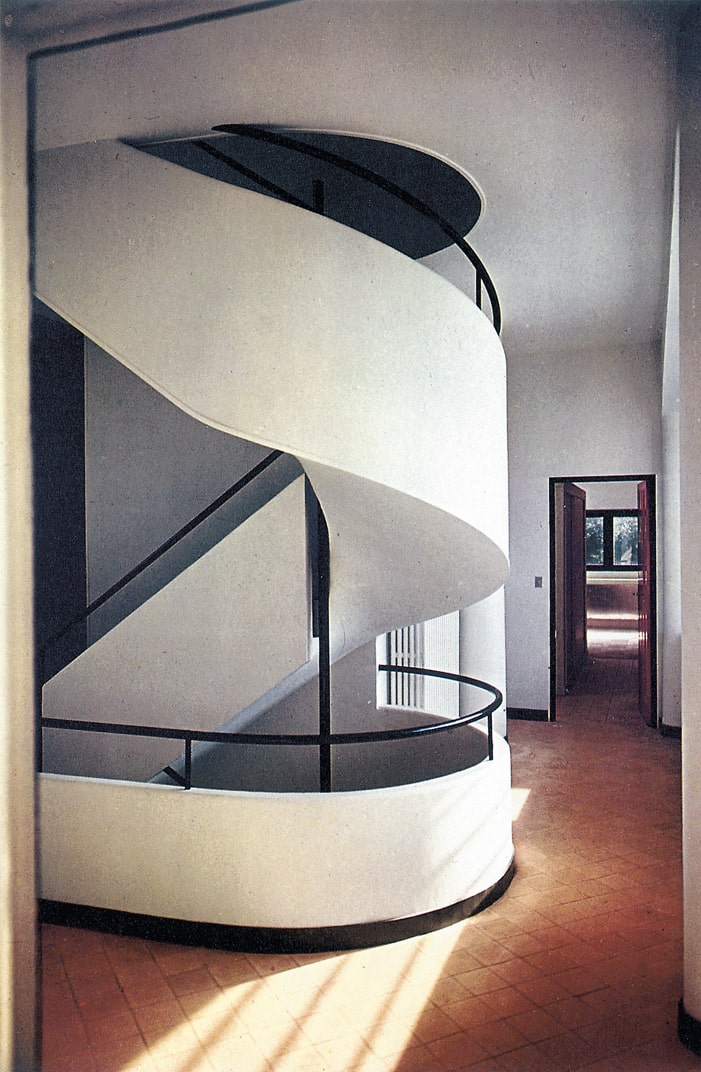 White helical staircase inside Villa Savoye in Poissy, with a dark handrail