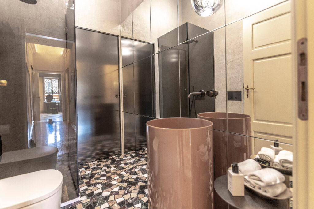 Bagno padronale con lavabo rosato e mosaico geometrico a Casa Trezza