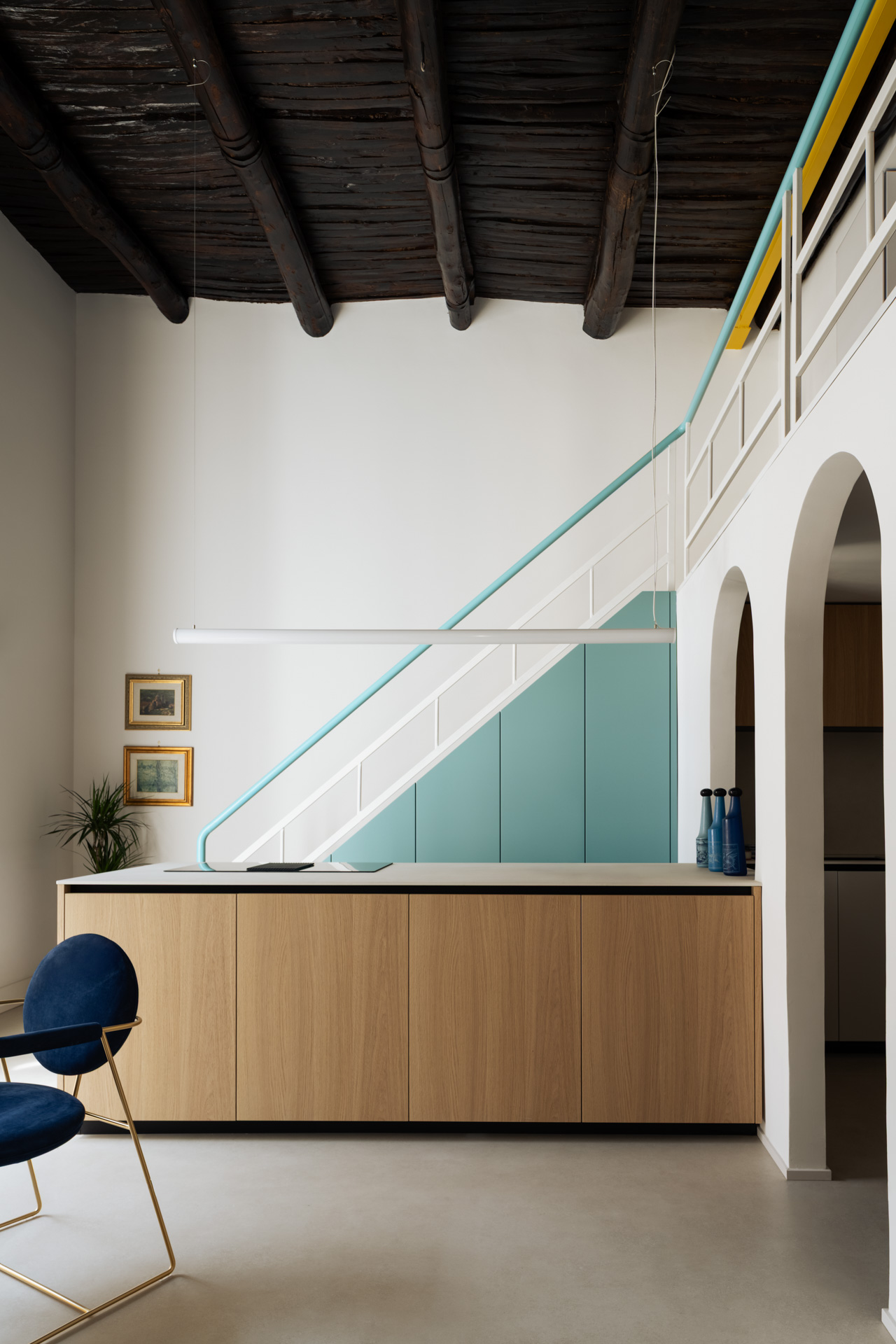Cucina di Casa Iolascon a Napoli con isola in rovere, scala verde acqua e soffitto ligneo restaurato