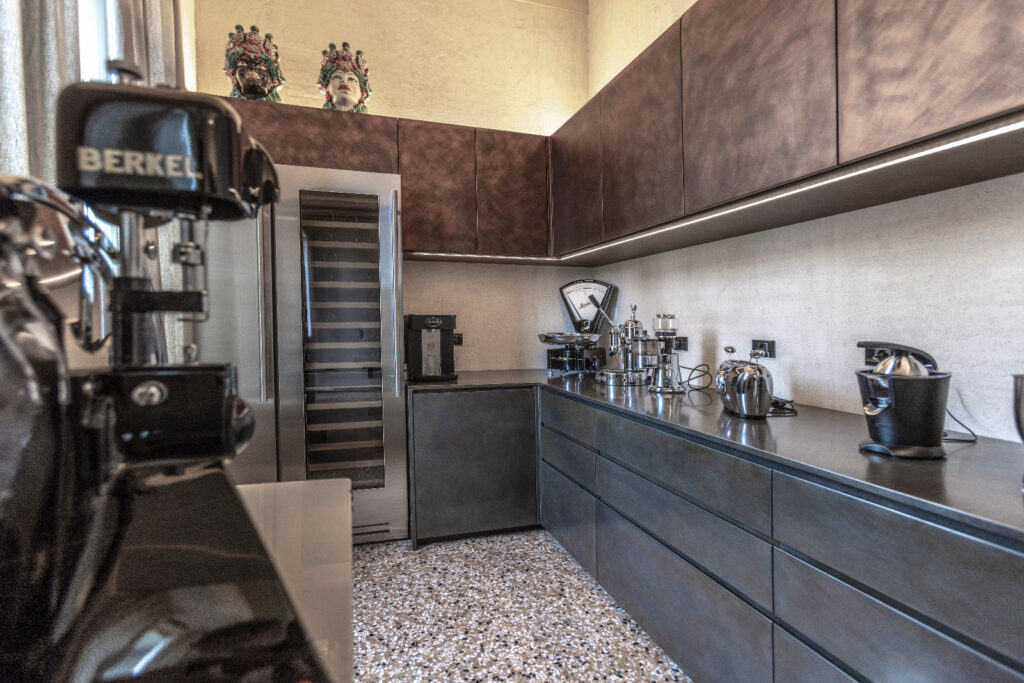 Cucina con volumi bruniti e terrazzo alla veneziana a Casa Trezza