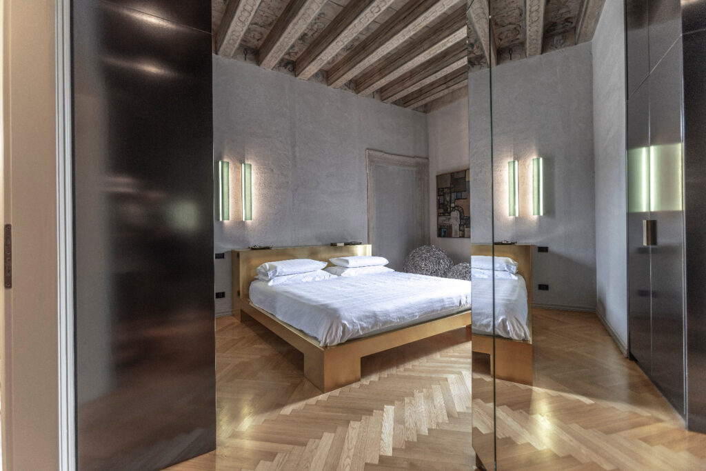 Camera da letto con letto dorato e parquet a spina di pesce a Casa Trezza