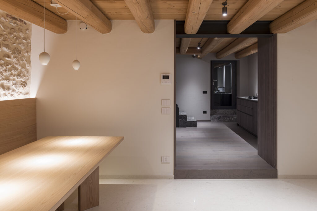 Pietra a vista, travi in legno e imbotti scuri a Casa EB, progetto Blocco 18