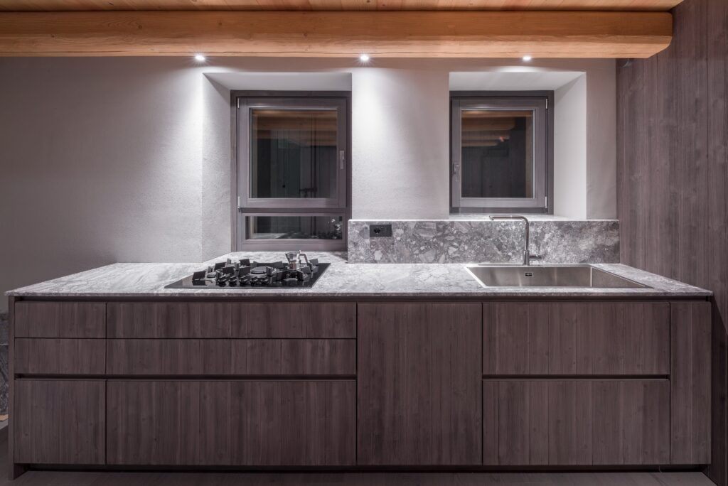 Cucina in legno scuro con piano in pietra grigia venata a Casa EB
