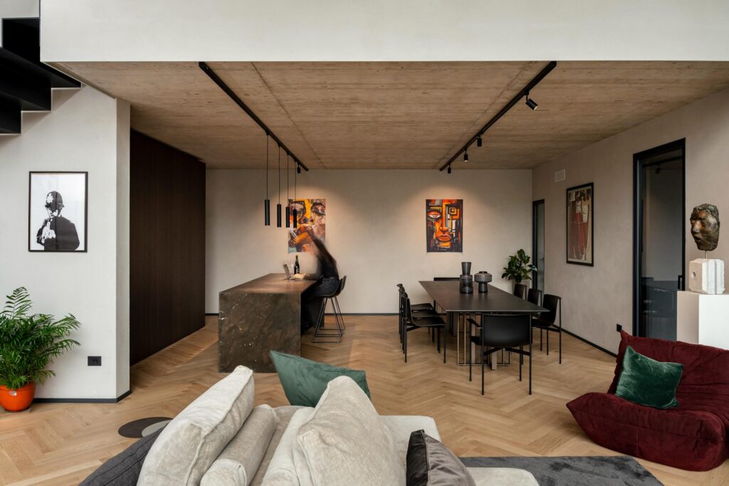 Open space di House B con isola in pietra scura e soffitto in calcestruzzo, progetto Enrico Pasti