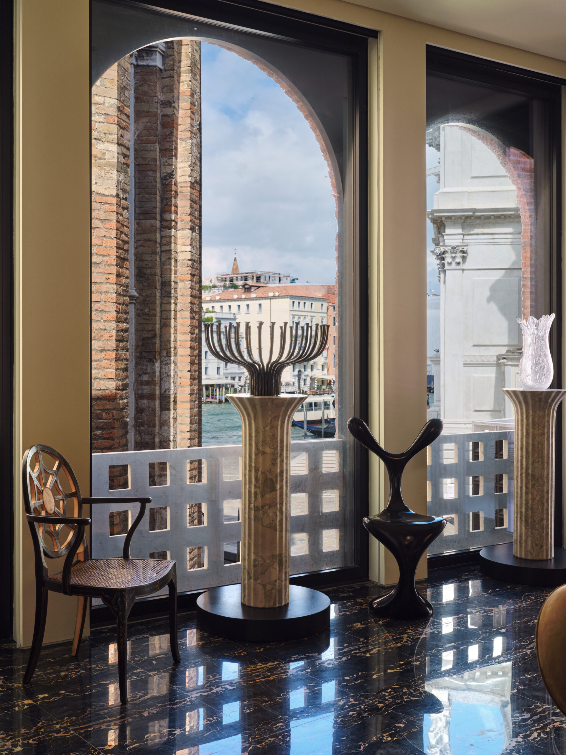 Arched windows, chairs and sculptural objects on plinths at Ca' Riflesso, overlooking Venice