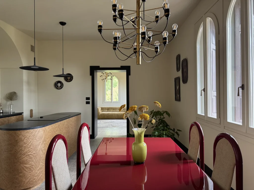 Tavolo bordeaux e finestre ad arco Liberty nel progetto Warm Minimalism