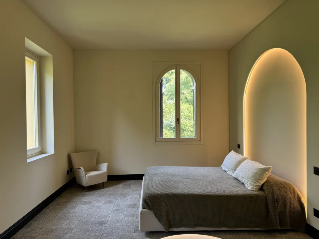 Camera da letto con nicchia ad arco retroilluminata nel progetto Warm Minimalism