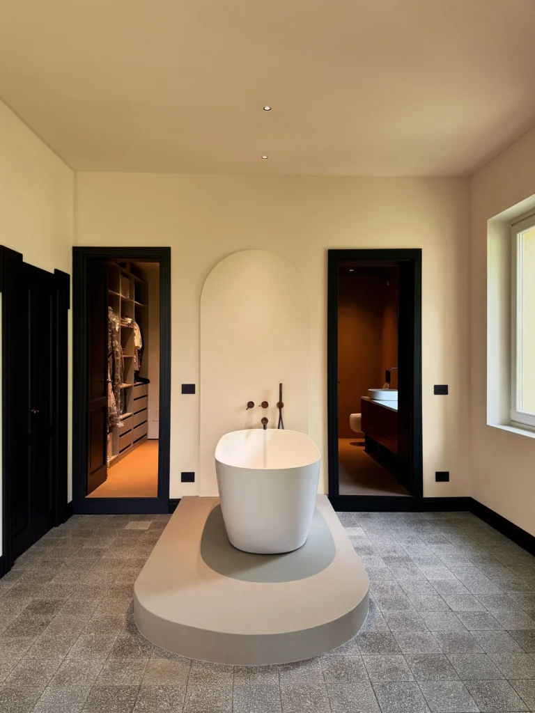Vasca freestanding su pedana e nicchia ad arco nel bagno di Warm Minimalism
