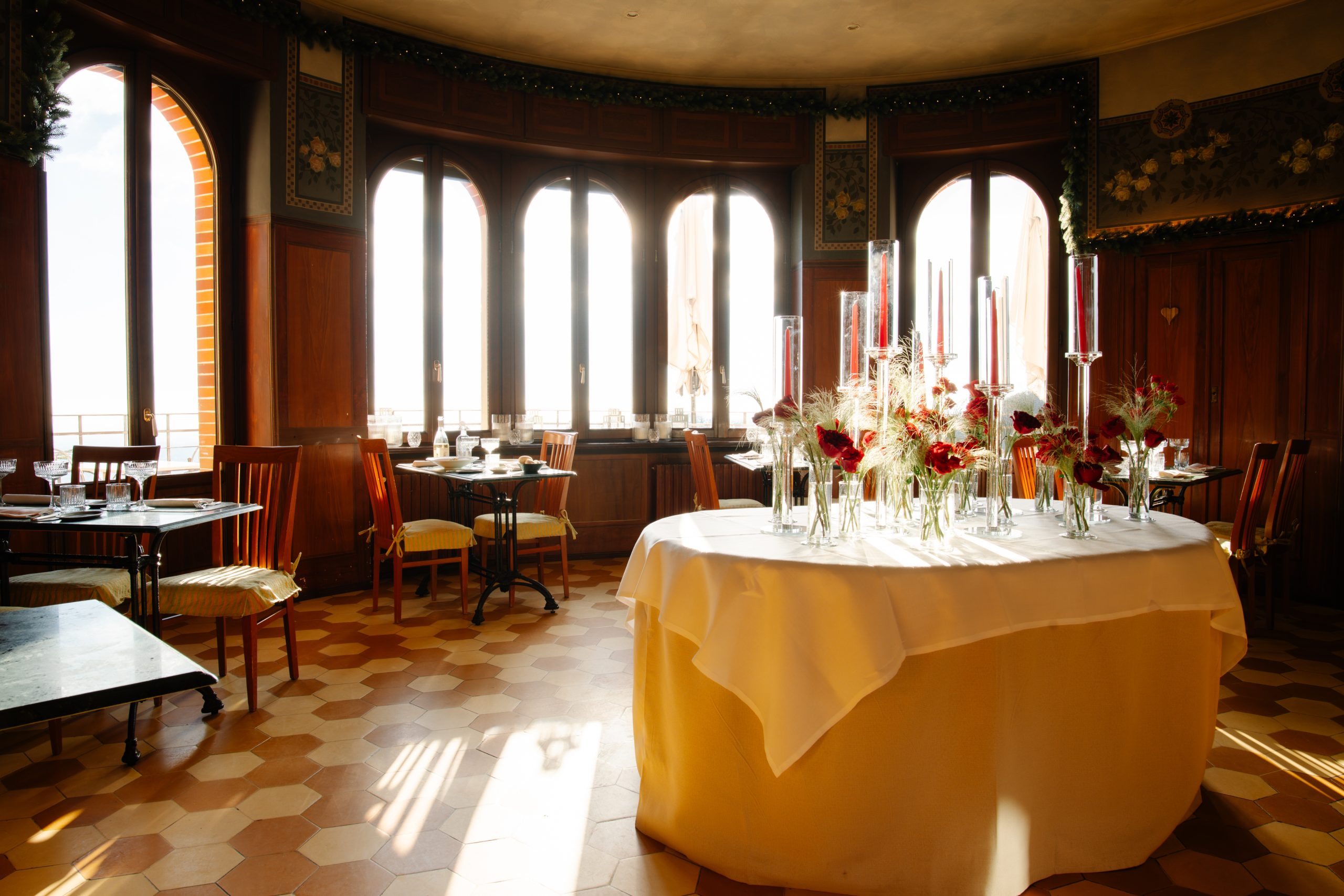 The oval room at Al Borducan in Sacro Monte di Varese, with timber panelling, arched windows and a geometric floor.