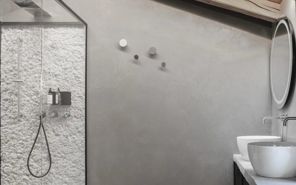 Bagno ensuite con pareti in resina e lavabi scultorei a Corte Lanfranconi