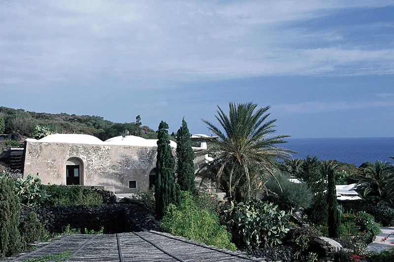 Dammusi con cupole bianche, palme e cipressi affacciati sul mare a Pantelleria