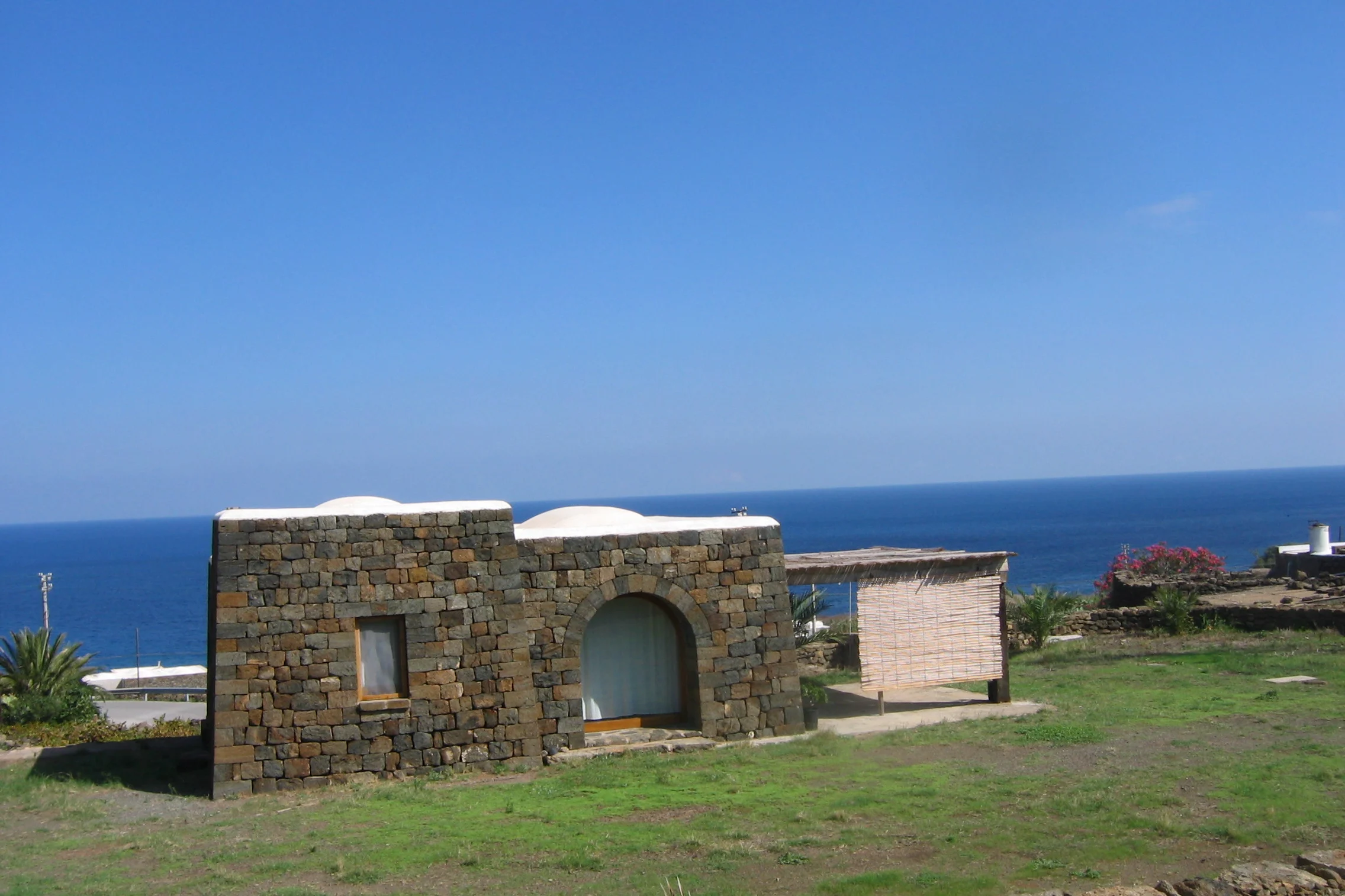 Dammuso di Pantelleria con muri in pietra e tetto imbiancato a calce, vista sul mare