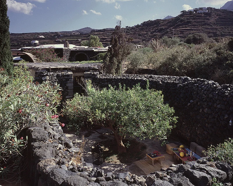 Giardino tra muri di pietra lavica e vegetazione mediterranea a Pantelleria