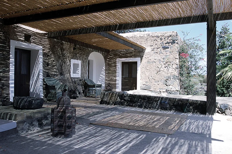 Patio con pergola, muri in pietra e tende tra i dammusi di Pantelleria