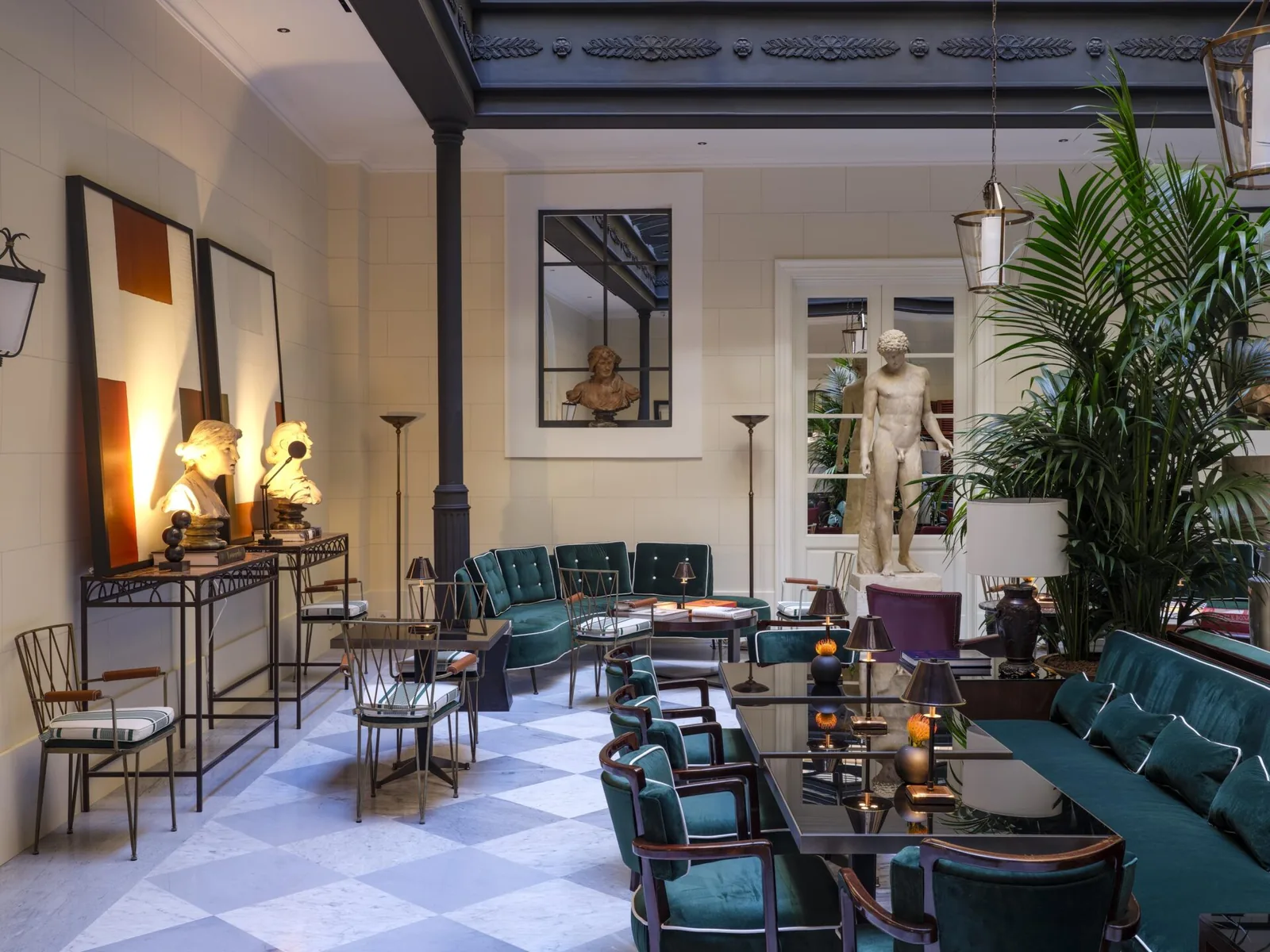 Salone di Casa J.K. Place Roma con sedute in velluto verde, opere d'arte e sculture classiche
