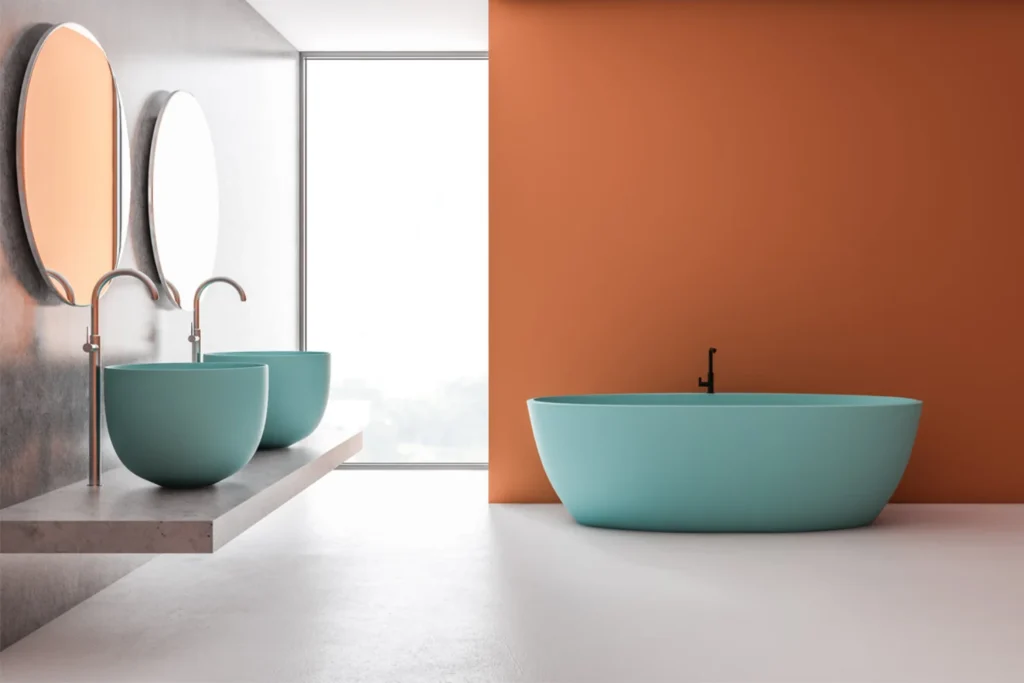 Vasca freestanding turchese davanti a una parete color terracotta