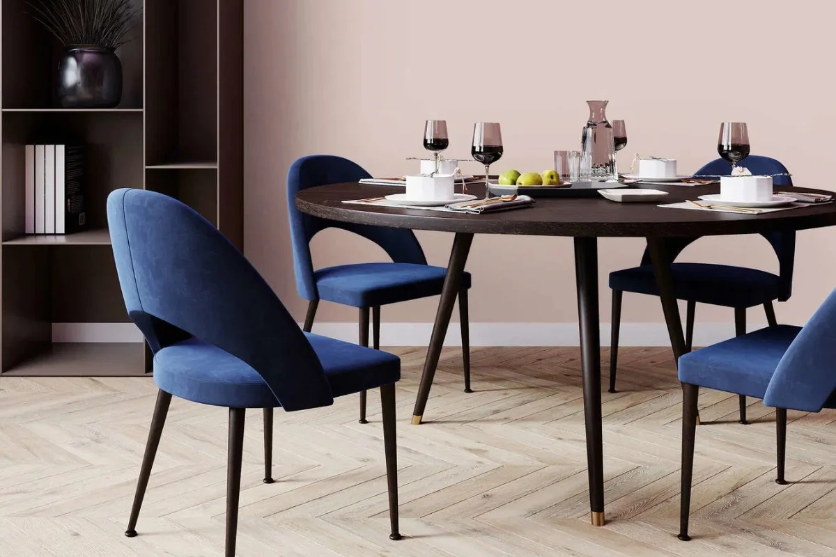 Parete rosa polveroso con sedie da pranzo imbottite blu