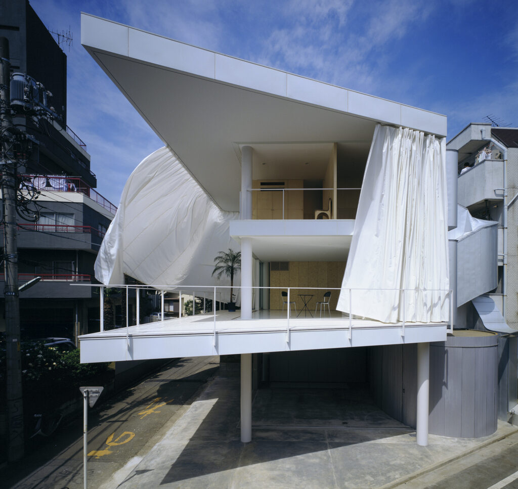 Facciata della Curtain Wall House con grandi teli bianchi aperti davanti alla terrazza