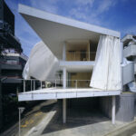 Facciata della Curtain Wall House con grandi teli bianchi aperti davanti alla terrazza