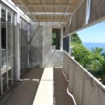 Balcone di E-1027 con finestre a libro, tenda ombreggiante e vista sul Mediterraneo tra i pini