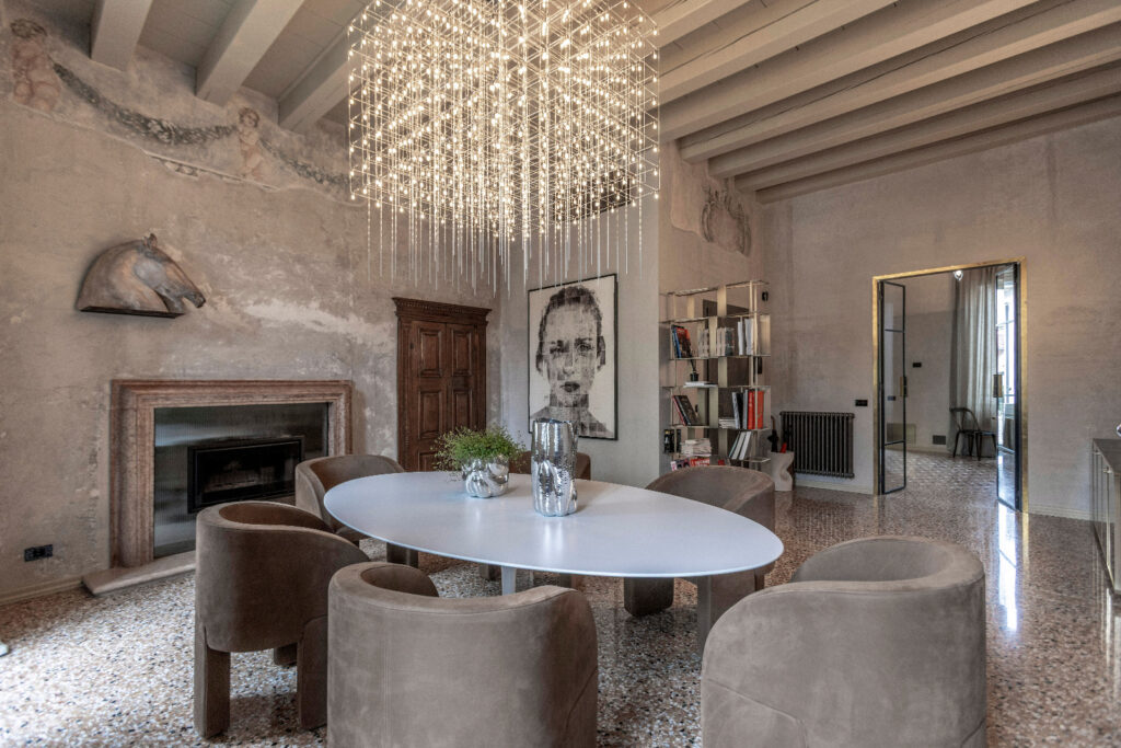 Zona pranzo di Casa Trezza con soffitto a travi, fregi affrescati e terrazzo alla veneziana