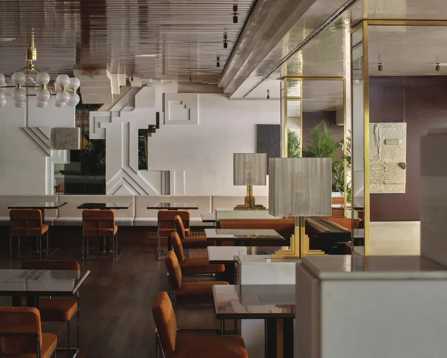 Sala ristorante dell’Hotel Aurora a Merano con sedute arancioni e parete geometrica