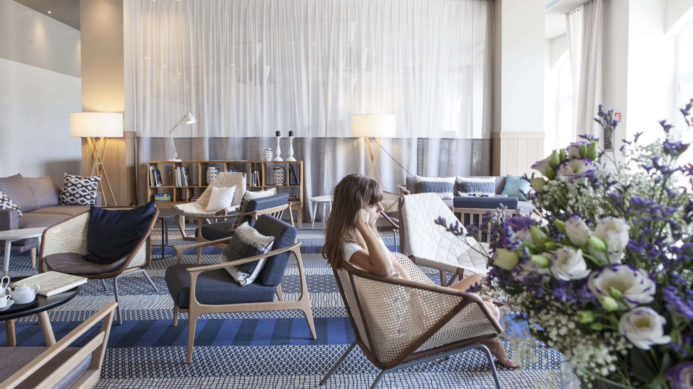Hotel de Charme Laveno lounge with timber armchairs, woven backs and blue textiles.