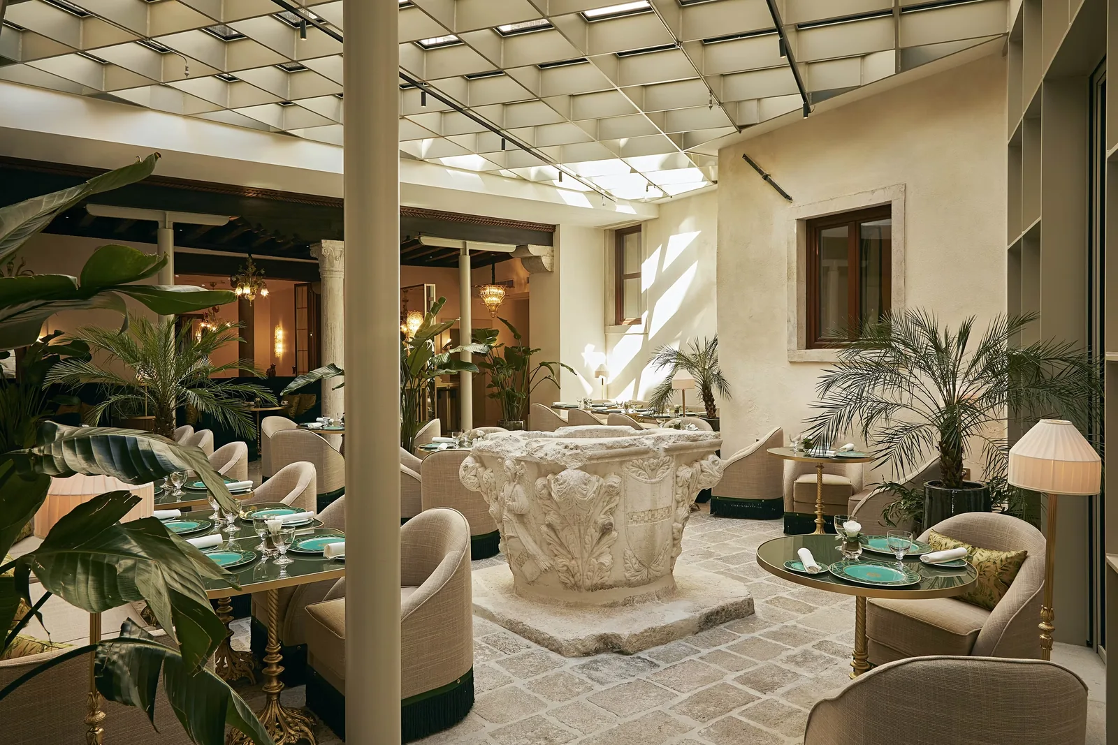 Lounge dell’Hotel Gabrielli a Venezia con sedute chiare, vegetazione e superfici storiche