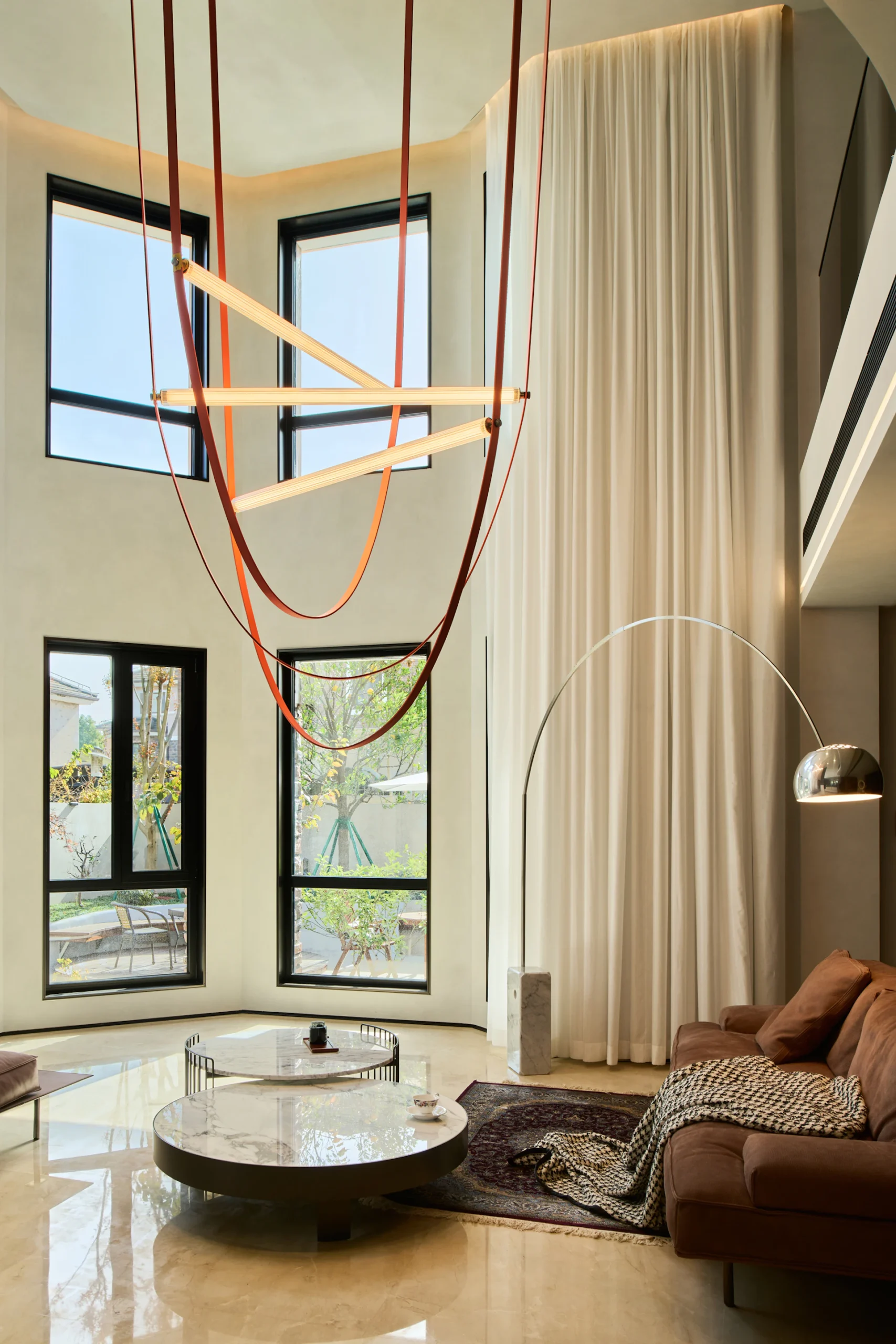 Soggiorno a doppia altezza con illuminazione decorativa e lampade Flos