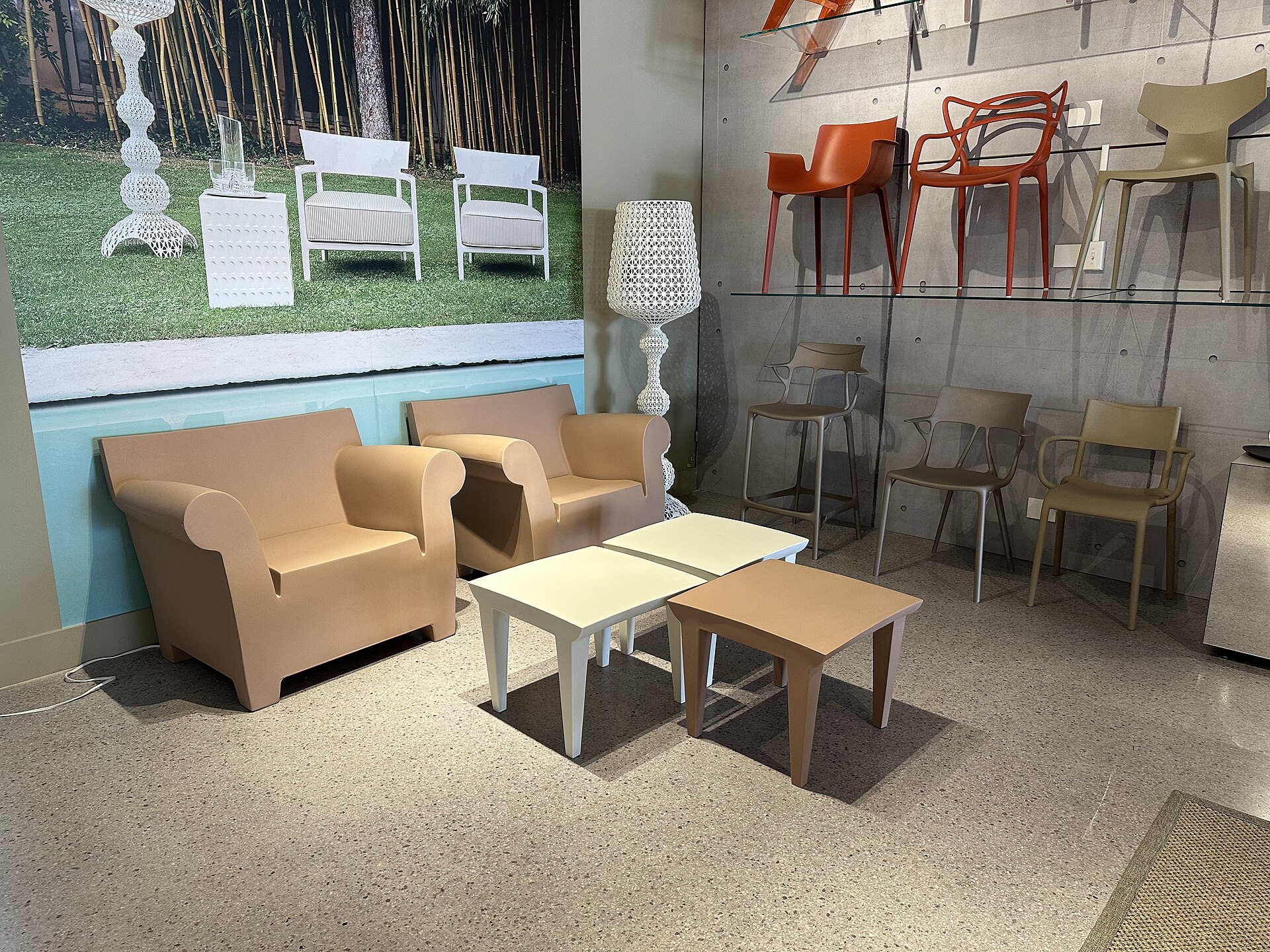 Sedie, tavolini e lampade Kartell esposti in uno showroom
