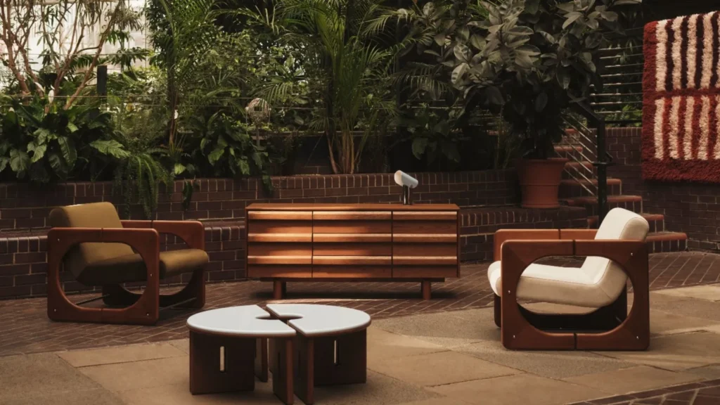 Poltrone, tavolini e credenza MADE x Barbican fotografati tra le piante del complesso londinese