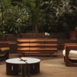 Poltrone, tavolini e credenza MADE x Barbican fotografati tra le piante del complesso londinese