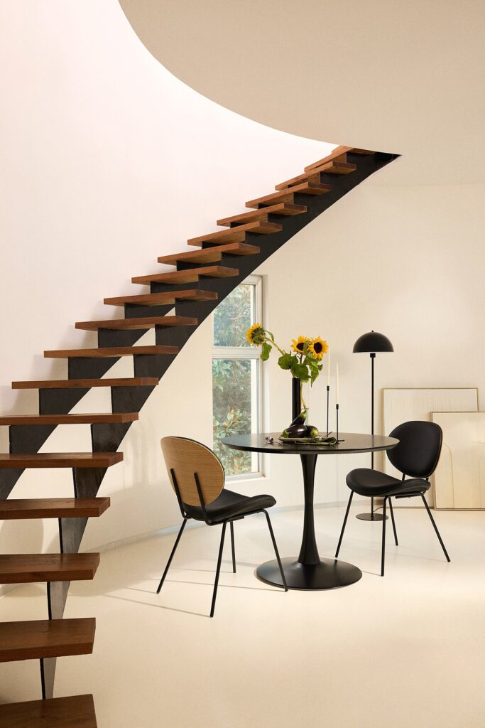 Ambiente Maisons du Monde con scala in legno, tavolo nero e sedie
