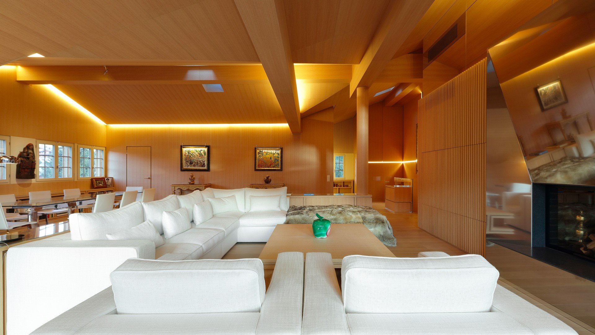 Soggiorno mansardato in legno con divani bianchi e illuminazione integrata