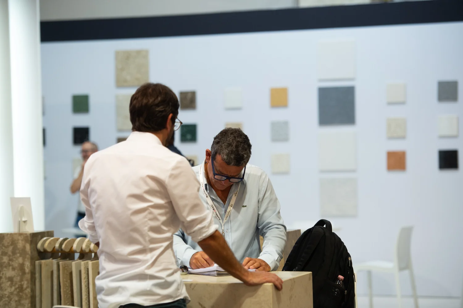 Visitatori a confronto davanti a campioni di materiali a Marmomac 2025