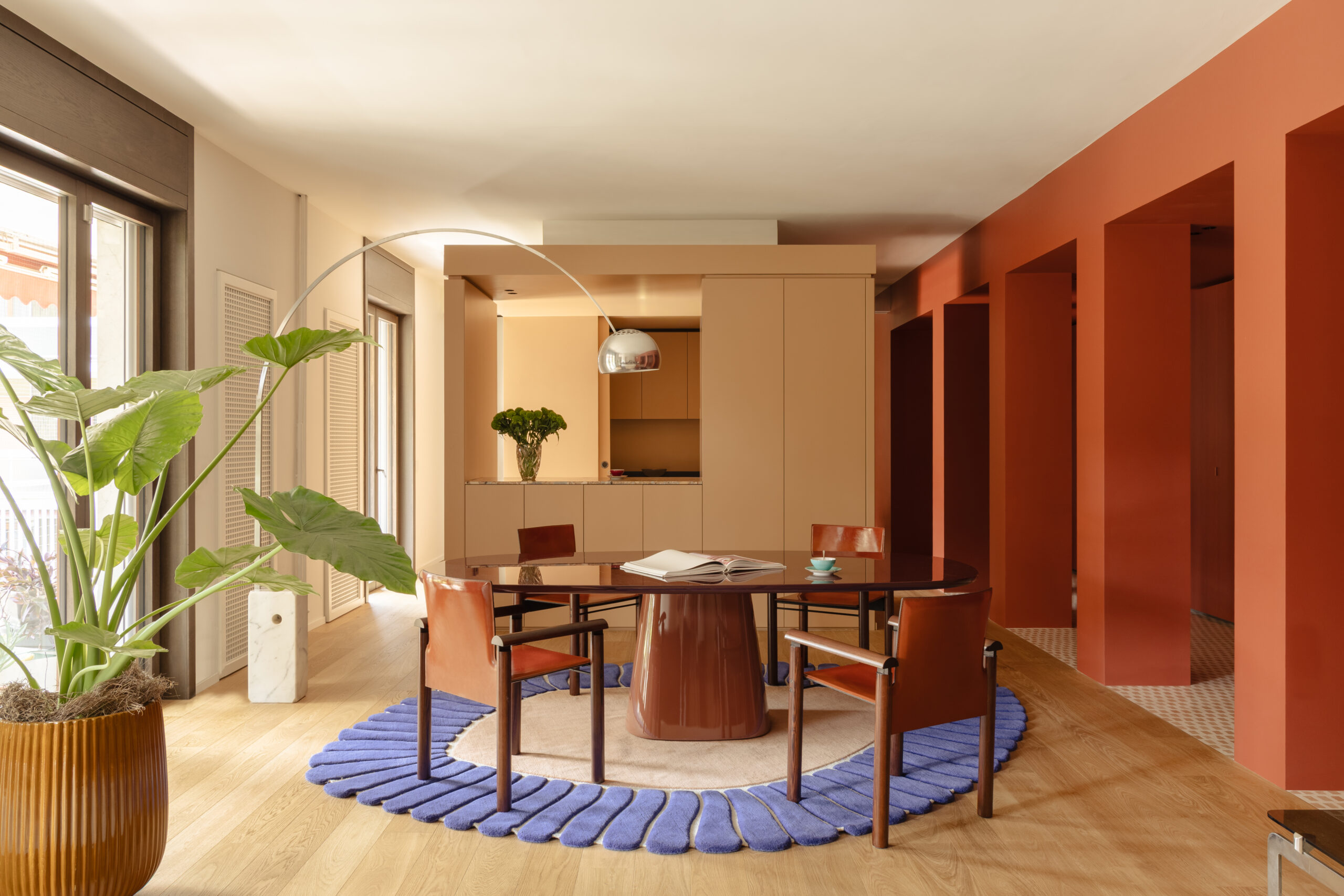 Zona pranzo di THAT Z SHOW con tavolo marrone, tappeto bordato di viola, cucina beige e porticato rosso terracotta.