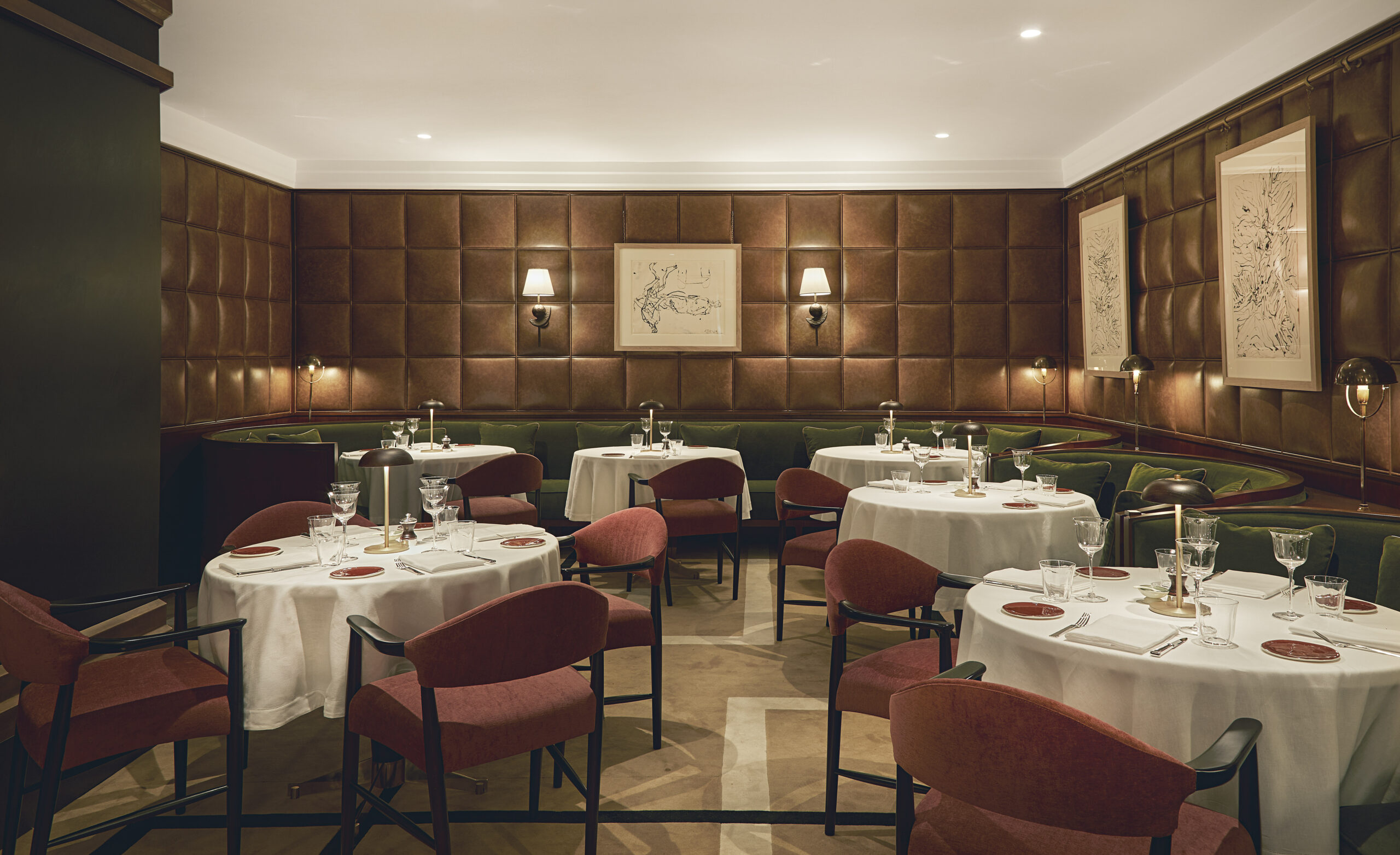 Ristorante Spiga con sedie rosa, panche verdi, tavoli apparecchiati e pareti rivestite a riquadri imbottiti.