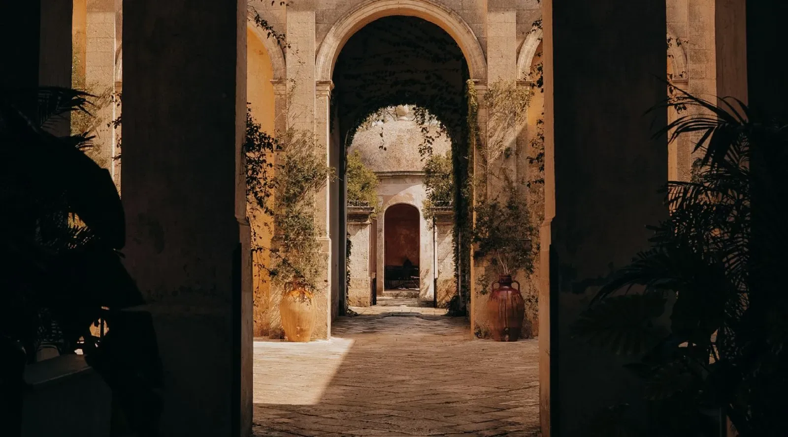 Sequenza di archi e pareti affrescate in una suite di Palazzo Daniele