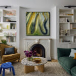 Living di Adelphi Townhouse con divano verde, poltrona senape, librerie e tappeto