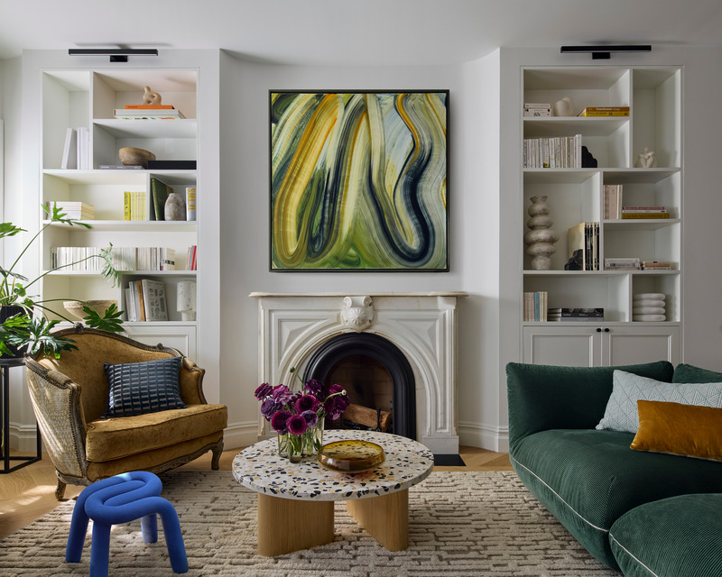 Living di Adelphi Townhouse con divano verde, poltrona senape, librerie e tappeto