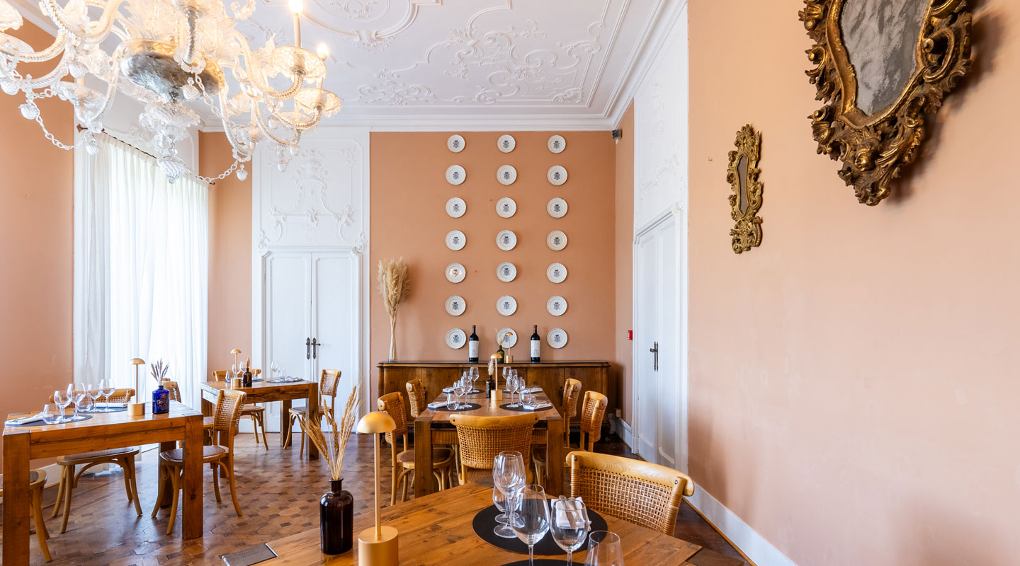 The O’Lac dining room at Villa Borghi, with pink walls, white stucco, a chandelier and woven chairs.