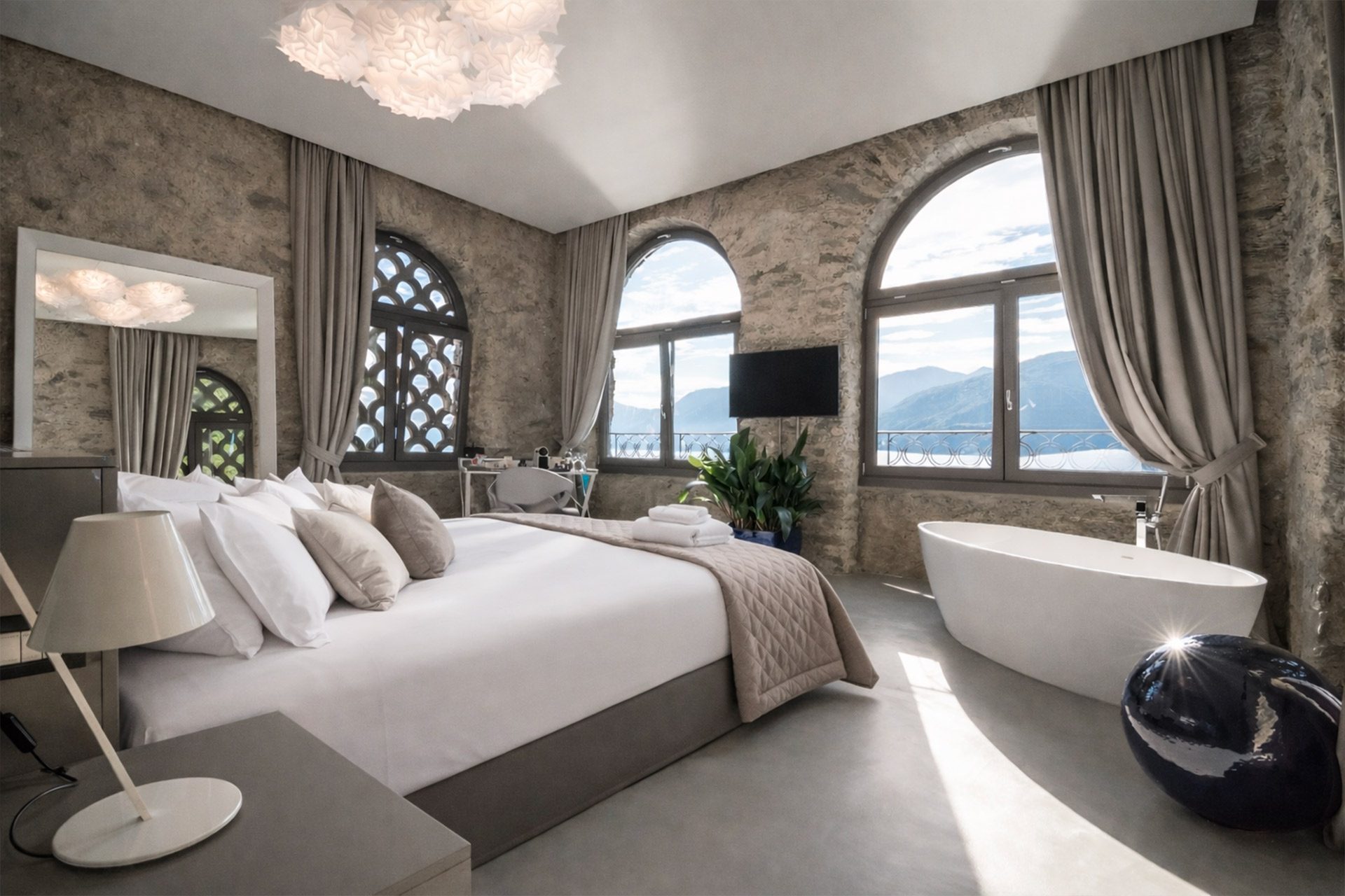 Prestige Suite at Villa Porta with arched windows, grey curtains and a freestanding bathtub.