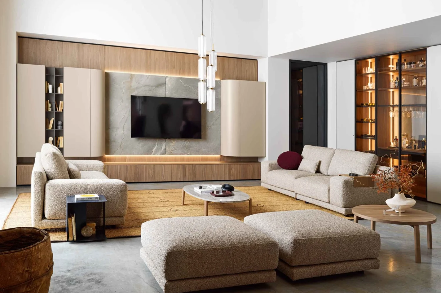 Living area with light wood wall unit, sofa and beige fabric ottomans