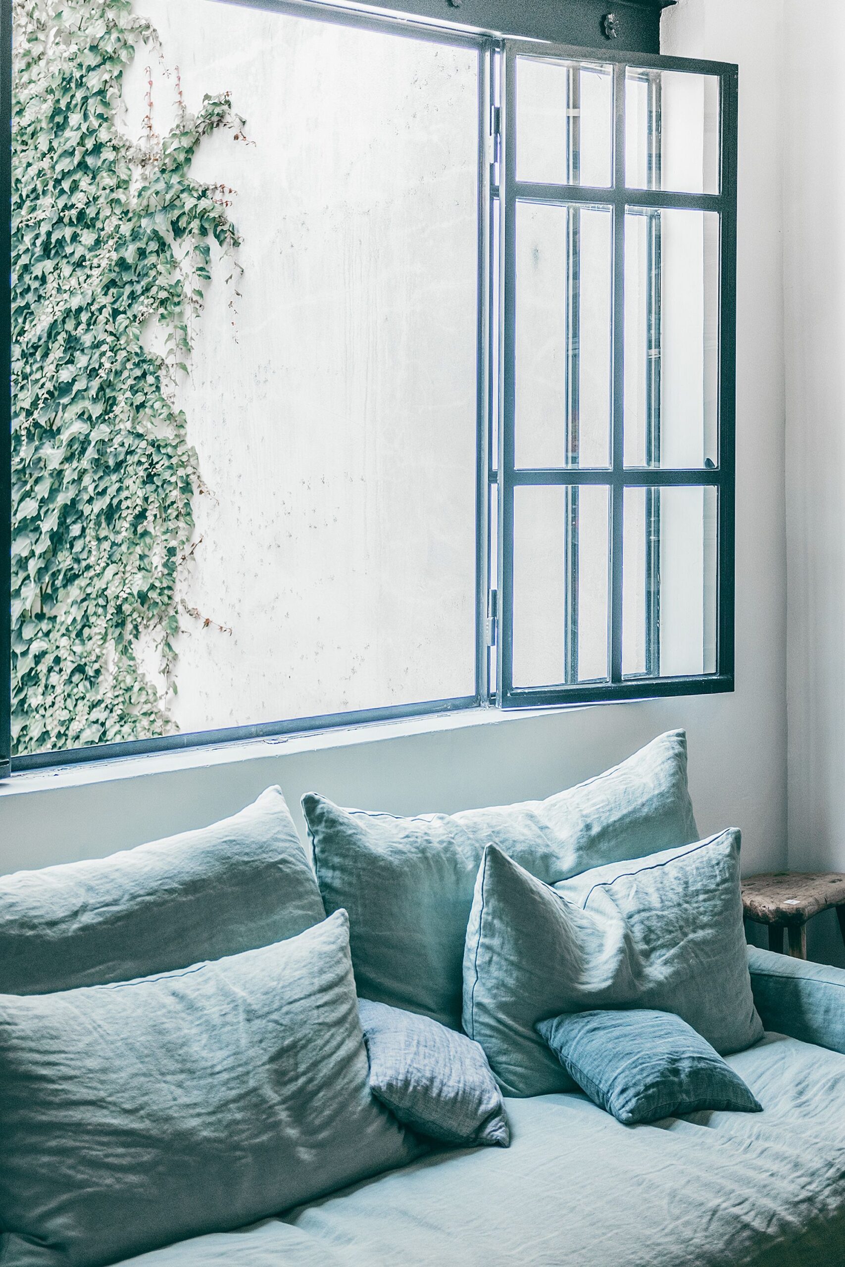 Divano blu con tessuti chiari e luce naturale