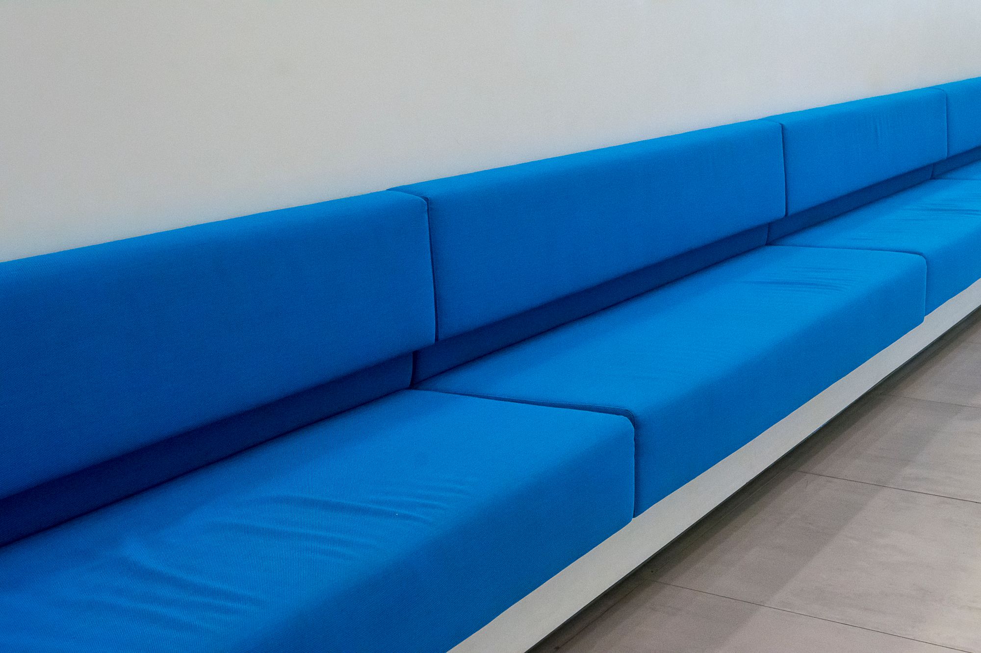 Divano blu intenso con parete chiara in soggiorno minimal