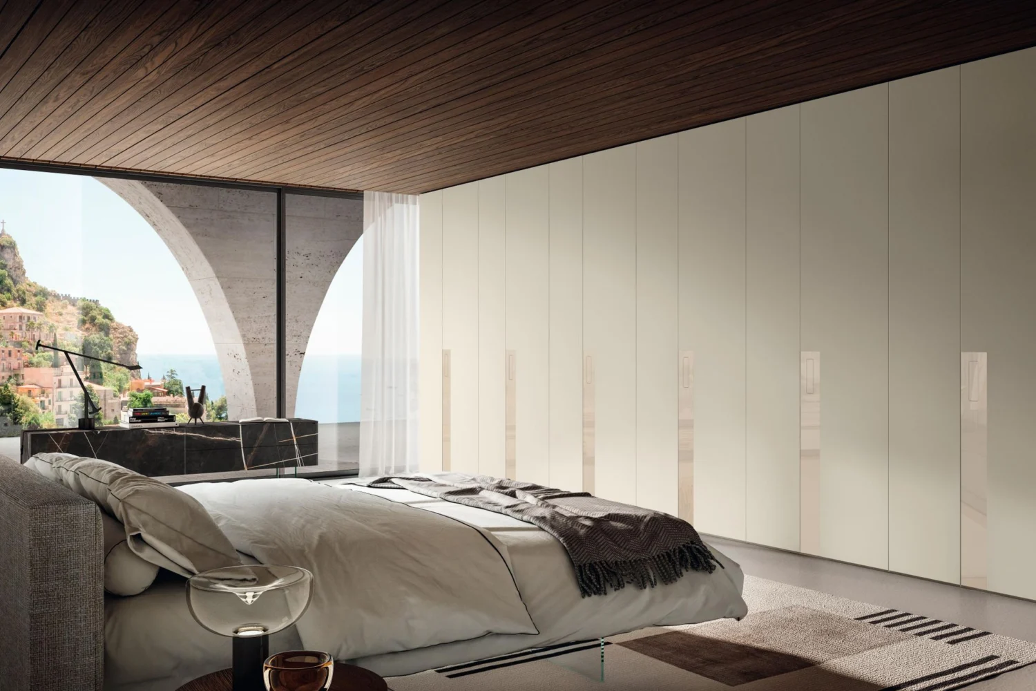 Full-wall white wardrobe with plain doors in a bright bedroom with a sea view