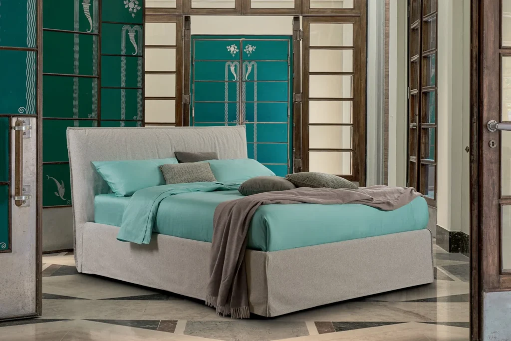 Bedroom with a pale upholstered bed, turquoise bedding and teal walls with decorated doors
