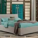 Camera da letto con letto imbottito chiaro, biancheria turchese e pareti verde petrolio con porte decorate